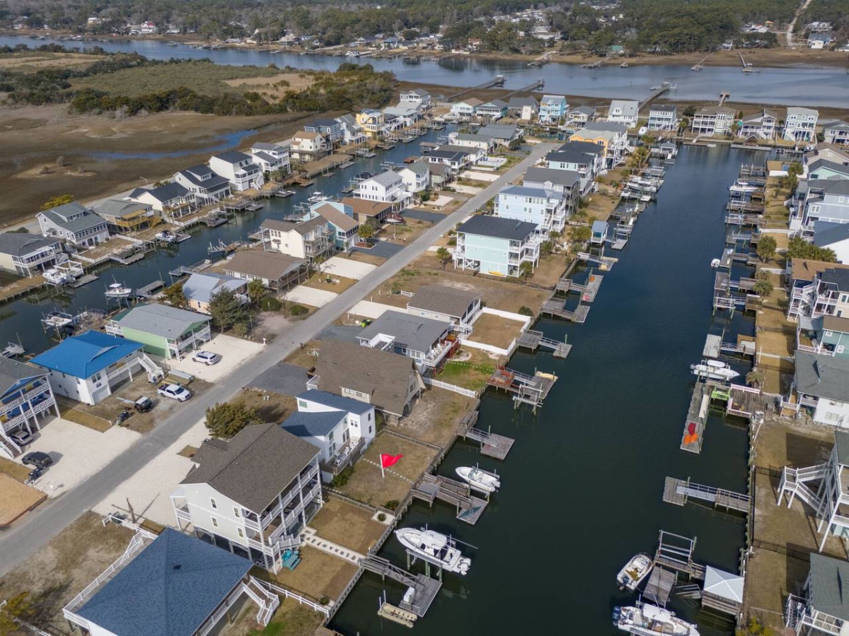13 - Book direct. Skip the fees. Aerial view of a waterfront residential neighborhood with houses built along narrow canals and docks for boats.